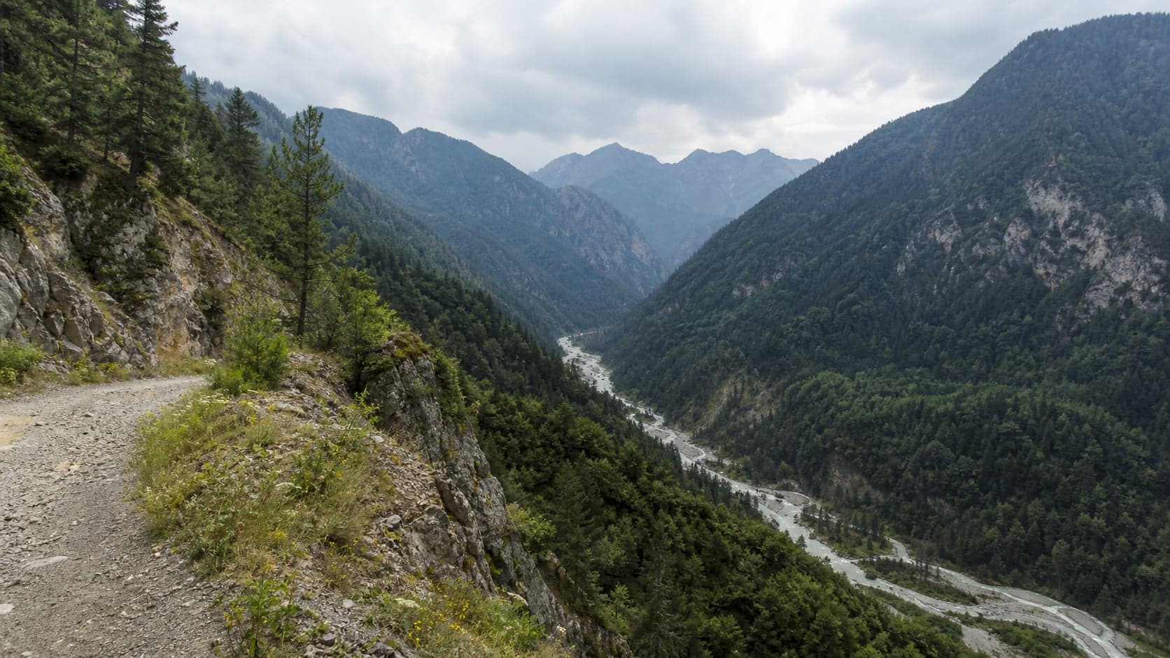 Кодорское ущелье: горная дорога над рекой, скальные склоны и лесистая долина.